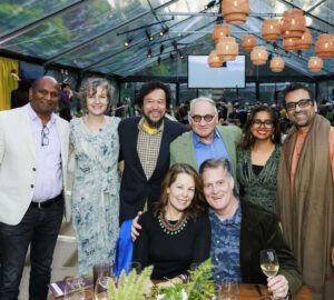 a group of people pose for the camera in an open-air event tent