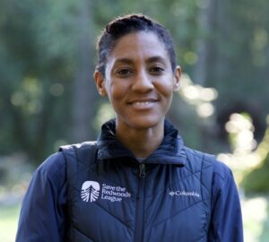 a woman wearing a Save the Redwoods vest smiles at the camera