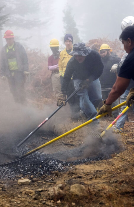indigenous fire tenders stewarding fire with rakes