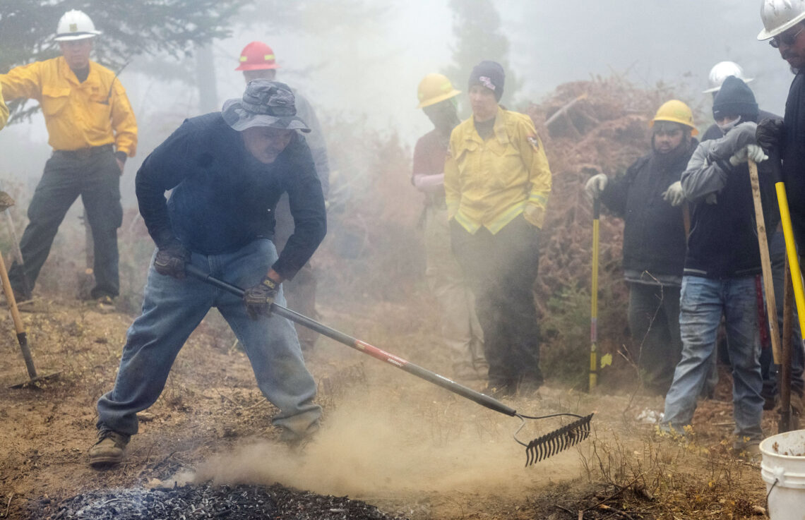 indigenous fire tenders stewarding fire with rakes