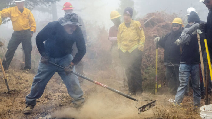 indigenous fire tenders stewarding fire with rakes
