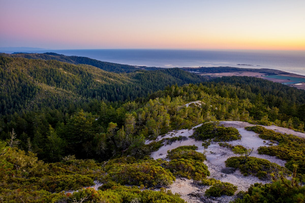  A scenic view of Cascade Creek at sunset with the Pacific coastline in the distance.