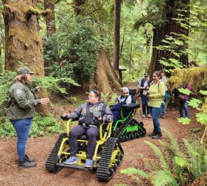 People ride in an electric all-terrain chair through Prairie Creek Redwoods.