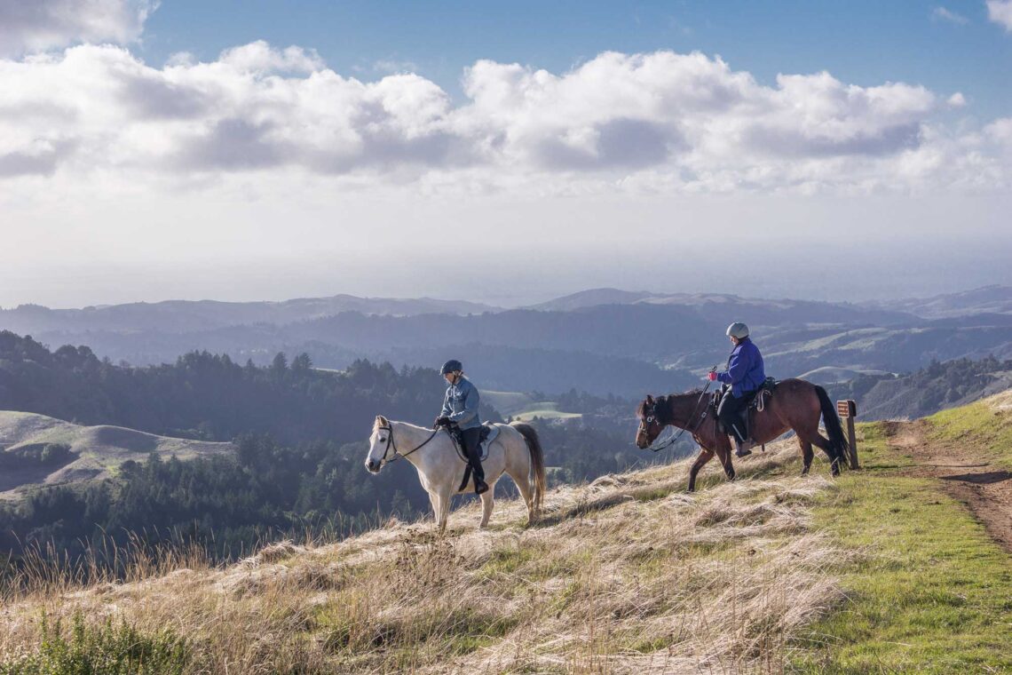 Two people on horseback atop a ridgeline overlooking the San Francisco peninsula.