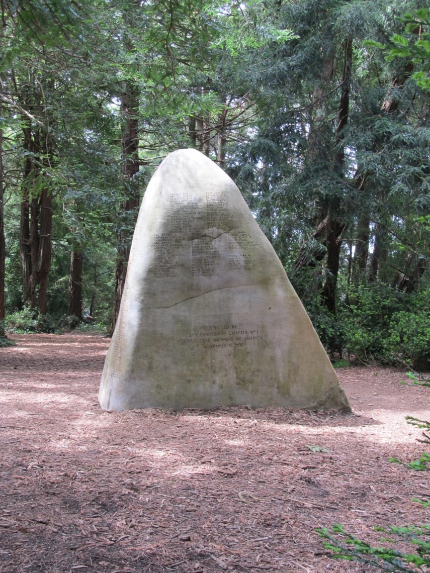 A tall rock memorial stands in a redwood grove
