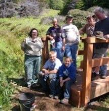 Joseph Haas (sitting, left) with a bridge he and his team built.