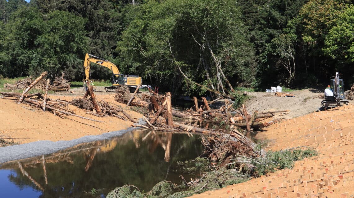 A construction site with a large excavator and a pond 