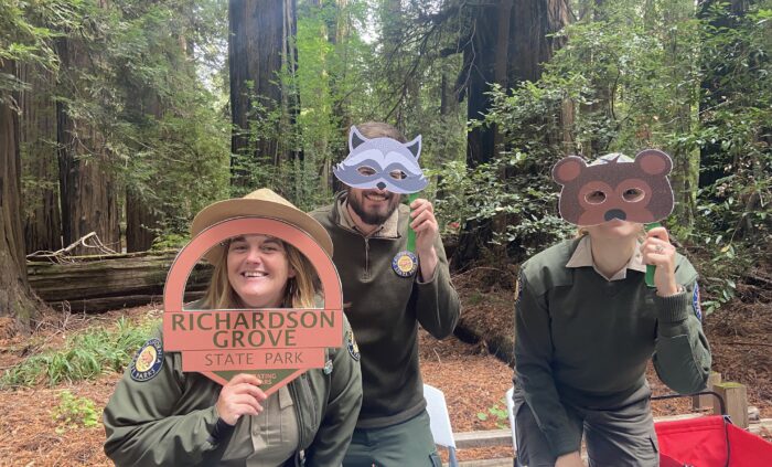 Park rangers hold up cutout animal masks and a Richardson Grove sign.