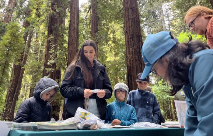 A woman with three children stops to check out a table.