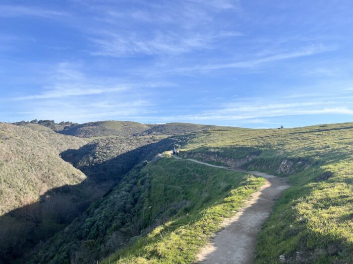 A wide trail leads through green hills. 