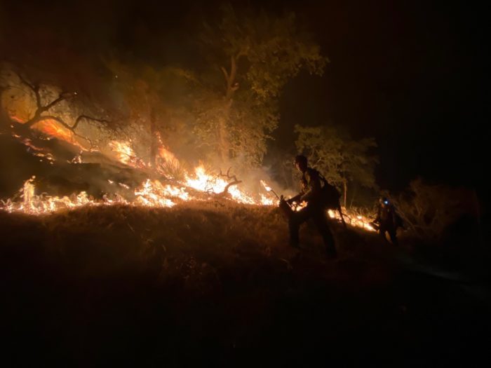 Firefighters working on a fire on a mountain at night