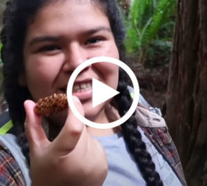 A Latina woman who is a student leader for Latino Outdoors holding a pinecone and smiling