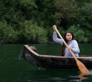 Young woman paddling a redwood canoe on the river
