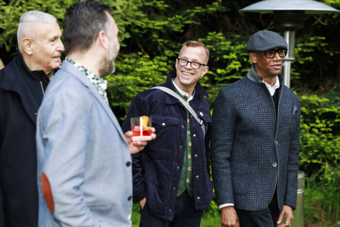 Four well-dressed men mingle outdoors