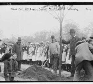 Adults plant a tree as dozens of schoolchildren watch in 1908.