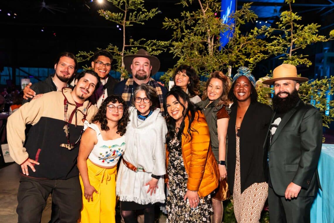 A group of young people in dressy outdoor gear pose for a photo
