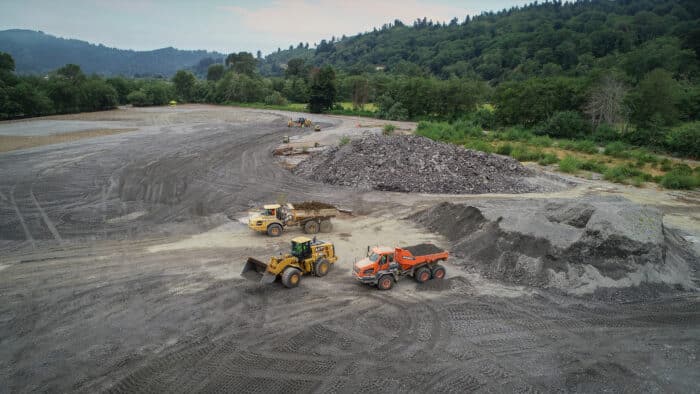 A group of construction vehicles in a dirt area
