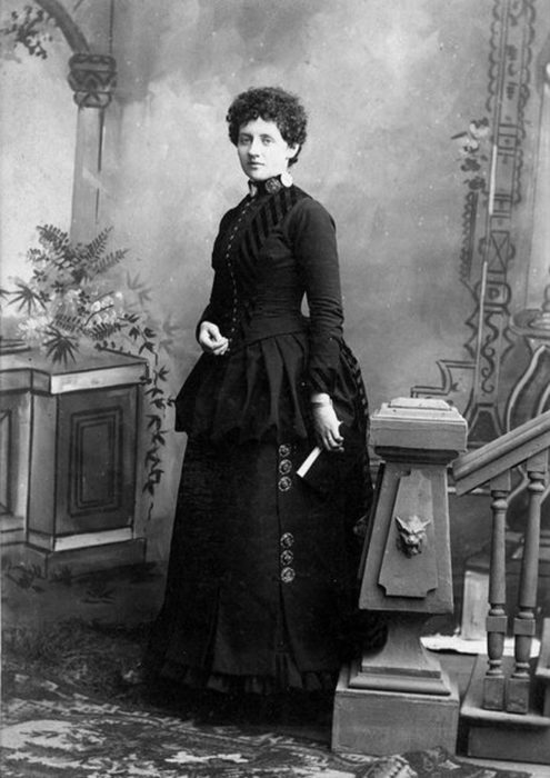 A black and white historical photograph of Laura Perrott Mahan, a white woman with dark, curly hair in a dark victorian-era dress