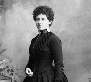 A black and white historical photograph of Laura Perrott Mahan, a white woman with dark, curly hair in a dark victorian-era dress