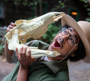 A smiling park holds up an animal skull.