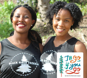 Two black women smiling, one with long braided hair and the other with chin length curls, wearing black tank tops with a circular logo featuring a tree and the words "Black Girls Trekkin"