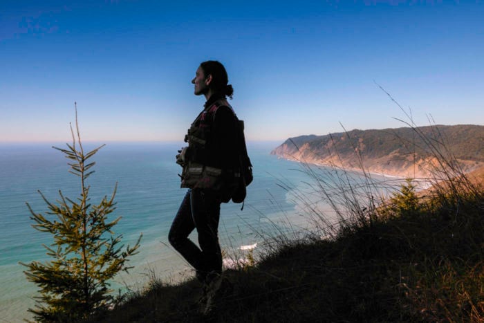 A smiling woman looks out over the coast line landscape