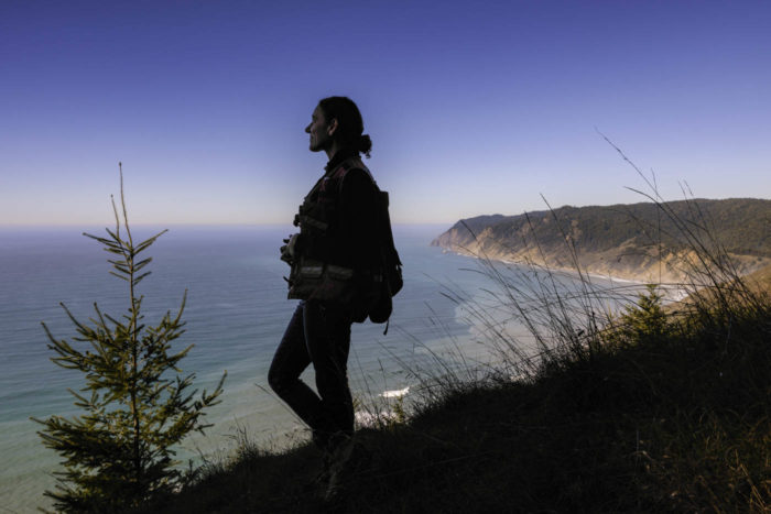 A smiling woman looks out over the coast line landscape