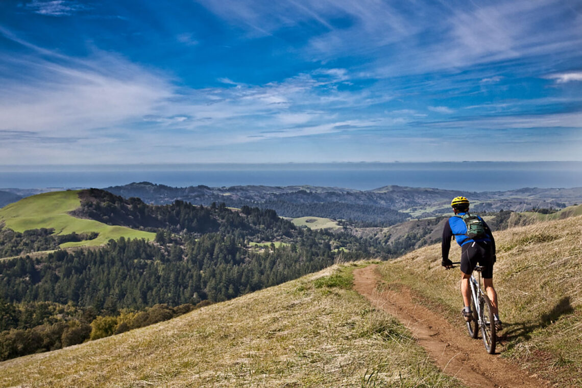 mountain biker on a ridgeline looking out over the San Francisco Bay Area peninsula.
