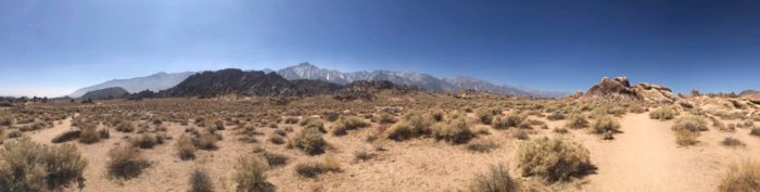 Panoramic shot of a desert landscape and a mountain in the distance.