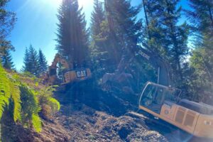 Excavators work in tandem to rebuild a slope.