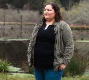 Rosie Clayburn stands in front of a restored pond and looks into the distance