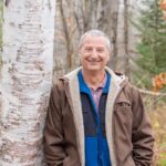 Chris Swanston leaning against a birch tree in autumn