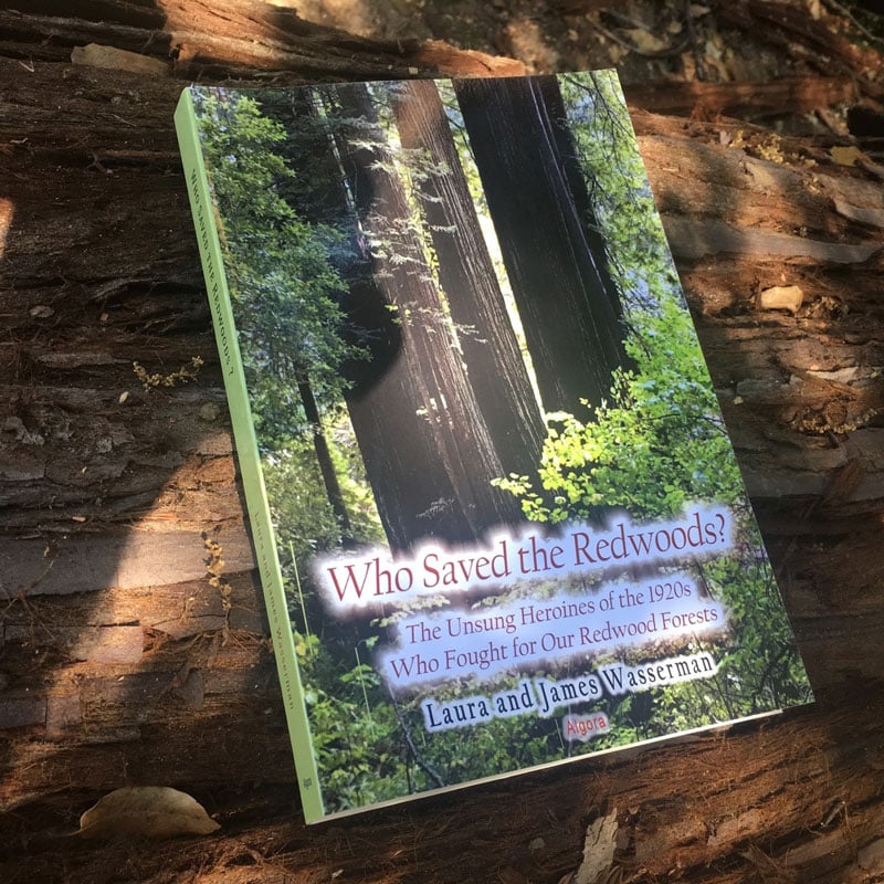 Book cover of Who Saved the Redwoods? The Unsung Heroines of the 1920s Who Fought for Our Redwood Forests by Laura and James Wasserman. The book is resting on a redwood log.