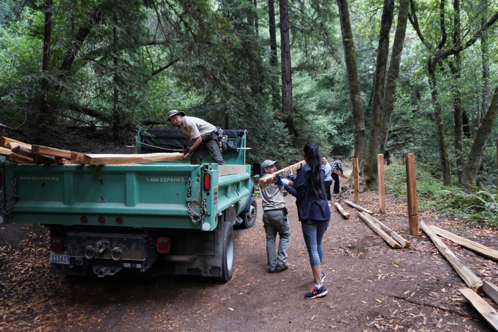 A volunteer carries a soon-to-be fence post to its designated hole.